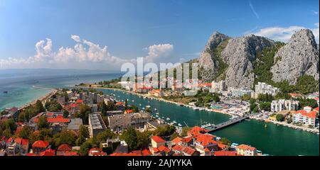 Omis città (Croazia) skyline, costa del mare, fiume con barche, montagne rocciose, soleggiato con le nuvole Foto Stock