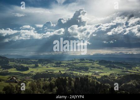 Colline e villaggi in Svizzera sotto un cielo nuvoloso e raggi solari Foto Stock