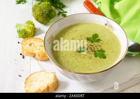 Menù dietetici. Mangiare sano concetto. Purea di zuppa di broccoli con crostini di aglio su un di legno bianco tavolo da cucina. Foto Stock
