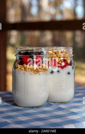 Yogurt, bacche, granola in vasetti di vetro Foto Stock