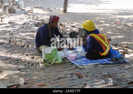 Pattaya, Thailandia - 23 Dicembre 2019: Pausa Pranzo. Operai di costruzione che mangiano nel mezzo di pavimentazione incompiuta. Foto Stock