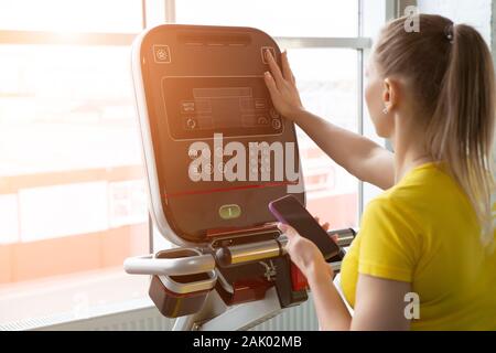 La donna le impostazioni di regolazione sulla macchina per allenamento in palestra Foto Stock