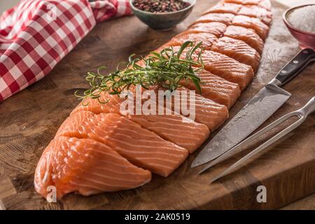 Intero crudo di filetto di salmone su una tavola di legno macellai di bordo Foto Stock