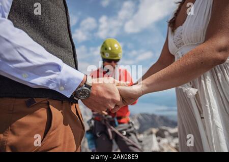 primo piano di coppia tenendo le mani mentre si sposano su una montagna Foto Stock