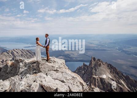 Sposa e Ginestra tengono le mani dopo essersi sposati sulla cima della montagna Foto Stock