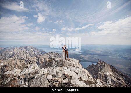 Coppia appena fatta bacia sulla cima di una splendida montagna rocciosa Foto Stock