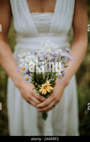 primo piano di sposa che tiene bouquet di nozze di fiori selvatici Foto Stock