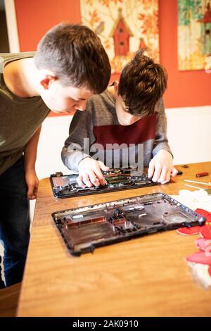 Due ragazzi adolescenti prendere di là di un vecchio computer portatile. Foto Stock