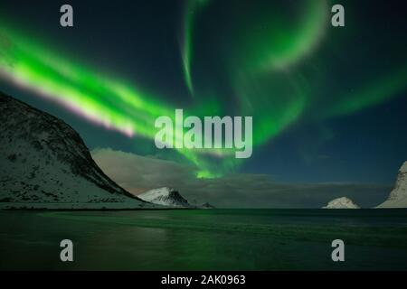 Luci del nord - Aurora Boreale riempire il cielo di montagne coperte di neve a Vik beach, Vestvågøy, Isole Lofoten in Norvegia Foto Stock