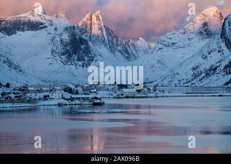 Prima luce splende su inverno cime oltre Reine e Kirkefjord, Moskenesøy, Isole Lofoten in Norvegia Foto Stock