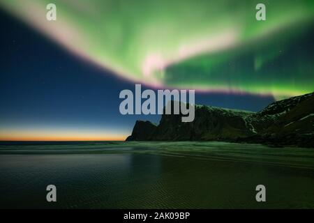 Spettacolari luci del nord - Aurora Boreale riempire il cielo sopra Kvalvika beach e sulle montagne circostanti, Lofotodden National Park, Moskenesøy, Lofoten è Foto Stock