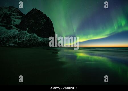 Spettacolari luci del nord - Aurora Boreale riempire il cielo sopra Kvalvika beach e sulle montagne circostanti, Lofotodden National Park, Moskenesøy, Lofoten è Foto Stock