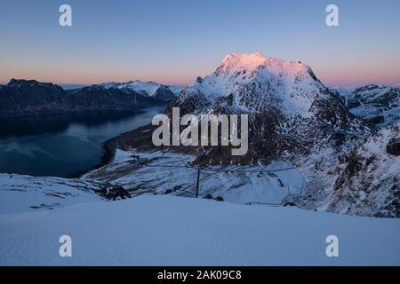 Himmeltindan picchi di montagna con un incremento di oltre il villaggio Uttakleiv ultimo cattura la luce solare, Vestvågøy, Isole Lofoten in Norvegia Foto Stock