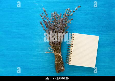 Il mazzetto di fiori viola situata in prossimità di un notebook su sfondo blu. Foto Stock