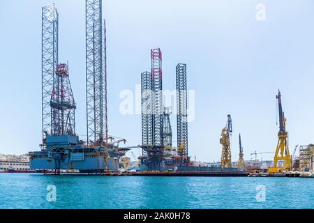 Le strutture con attrezzature per la perforazione di pozzi petroliferi si trova in mare nei pressi di una spiaggia di Malta sullo sfondo del cielo blu. Foto Stock