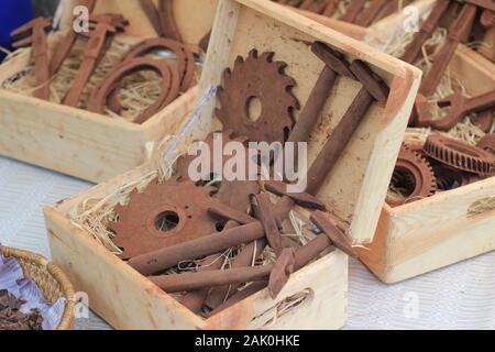 Strumenti di cioccolato, ingranaggi, calibri di misurazione per la vendita in una scatola di legno con paglia sulla strada del mercato di Vilnius, Lituania Foto Stock