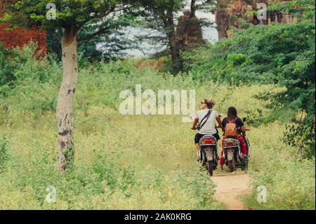 Donne Equitazione su ciclomotore elettrico durante la visione di vecchi templi di Bagan (Myanmar) Foto Stock