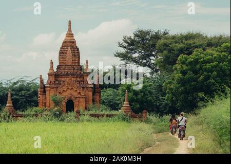 Le donne sul ciclomotore elettrico guardando vecchio tempio di Bagan (Myanmar) Foto Stock