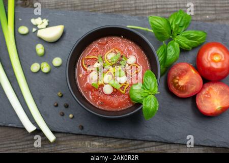 Mediterraneo zuppa di pomodoro in una piccola ciotola con cipolline, pepe e basilico. Vista da sopra Foto Stock