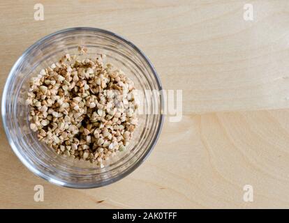 Il grano saraceno in un bicchiere su un tavolo di legno Foto Stock