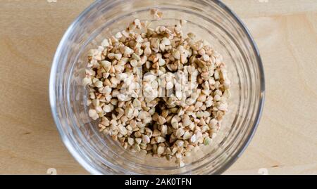 Il grano saraceno in un bicchiere su un tavolo di legno Foto Stock