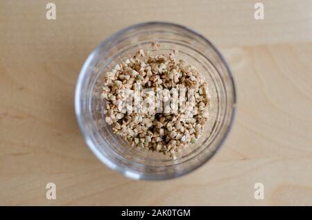 Il grano saraceno in un bicchiere su un tavolo di legno Foto Stock