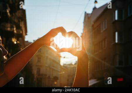 La donna le mani nel cuore di amore simbolo forma tramonto Foto Stock