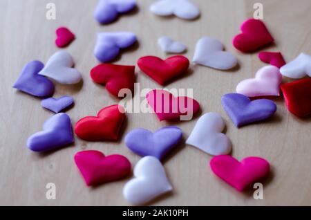 Cuori in diversi colori e dimensioni su di un tavolo di legno Foto Stock