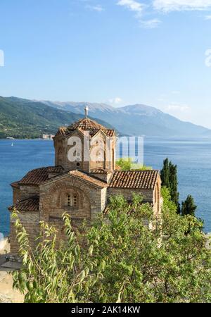 Vista superiore del San Giovanni il Teologo, Kaneo chiesa a Ohrid Macedonia nord con il lago di Ohrid e montagne sullo sfondo, verdi alberi intorno, Foto Stock