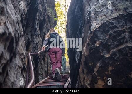 donna sale le scale attraverso una spaccatura nelle rocce Foto Stock