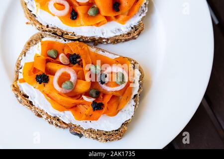 Vegano lox di carota - vegane Salmone affumicato sulla base di carote che viene servita su un sano del pane di pasta acida e rabboccato con cipolle, capperi e vegano caviale di alghe Foto Stock