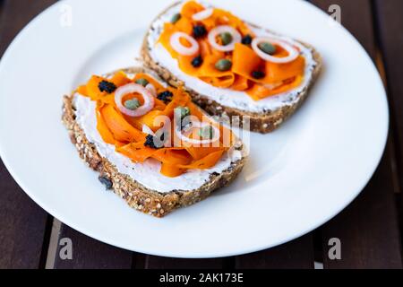 Vegano lox di carota - vegane Salmone affumicato sulla base di carote che viene servita su un sano del pane di pasta acida e rabboccato con cipolle, capperi e vegano caviale di alghe Foto Stock