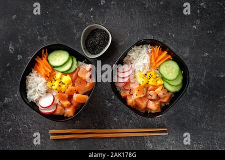 Vista dall'alto di due poke ciotole con salmone su sfondo nero. Spazio di copia Foto Stock