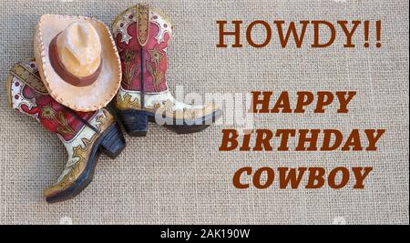 Stivali da cowboy e hat con howdy buon compleanno messaggio in ruggine testo colorato Foto Stock