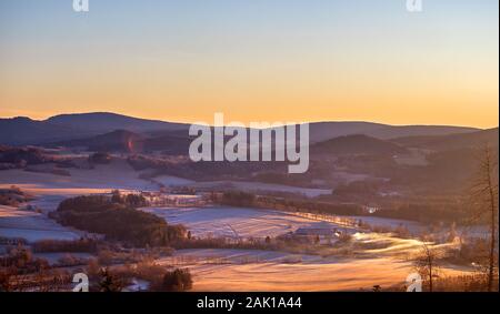 alba in montagna - inverno paesaggio collinare con boschi, alberi e prati (con brina e neve) Foto Stock