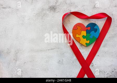 Multicolore in legno puzzle a forma di cuore su uno sfondo grigio. Concetto il giorno di san valentino, relazione. Foto Stock