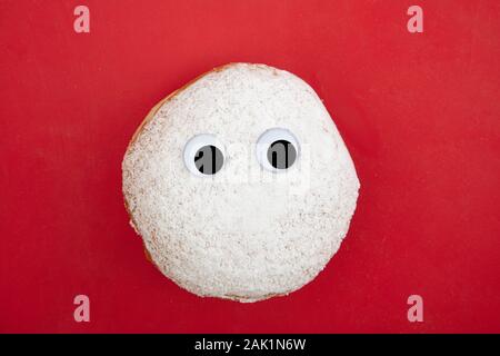 Berliner culinaria ciambella con strani occhi su sfondo rosso Foto Stock