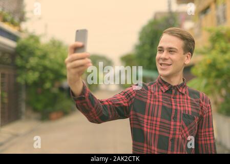 Giovane uomo bello indossare rosso a scacchi shirt nelle strade all'aperto Foto Stock