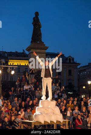 Un artista di strada esegue un atto di fronte ad una folla nella piazza principale, Cracovia, Polonia Foto Stock