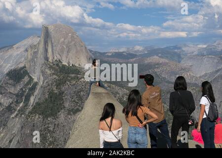 Ragazza turistica che posa per una foto con gruppo di amici ammirando Half Dome Foto Stock