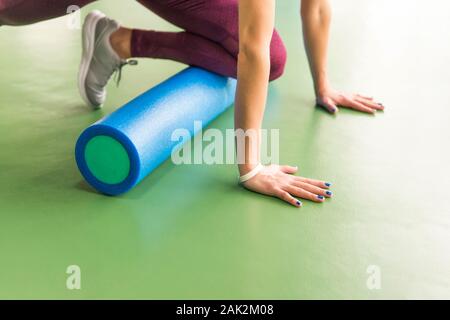 Femmina attraente facendo schiuma esercizio del rullo e che pongono nel moderno centro fitness Foto Stock