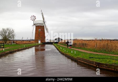 Una famiglia su un passeggiata invernale da Horsey Dyke avvicinando il Windpump su Norfolk Broads a Horsey, Norfolk, Inghilterra, Regno Unito, Europa. Foto Stock