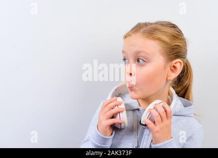 Bambino in grandi cuffie su sfondo bianco Foto Stock