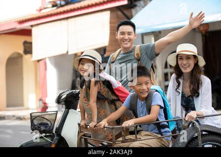 Felice giovane famiglia cinese guida tuk-tuk sulla strada Foto Stock