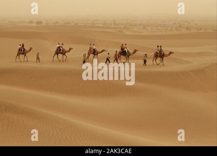 I turisti ad intraprendere un viaggio di cammello al deserto di Thar vicino a Sam nello stato federale del Rajasthan in India. Il Deserto di Thar è noto anche come grande India Foto Stock