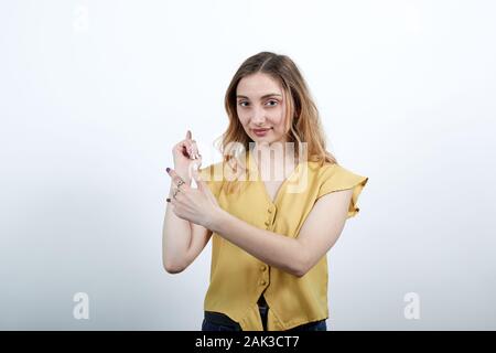 Giovane donna bionda puntando le dita dietro la schiena, guardando la telecamera, sorridente Foto Stock