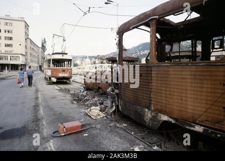 Il 17 agosto 1993 durante l'assedio di Sarajevo:un paio a piedi passato scatafascio tram lungo Obala dei Kulina Bana durante uno dei frequenti, anche se breve, ceasfires. Foto Stock