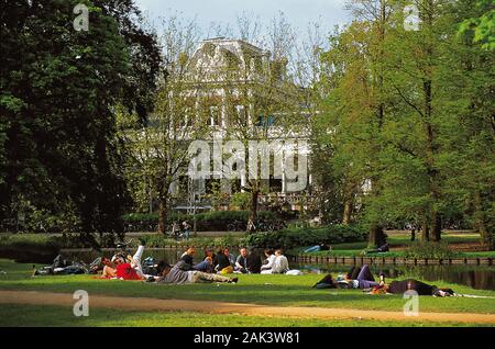 Persone relax su una zona per prendere il sole di fronte al Museo dei film nel Parco di Vondel Amsterdam. Il Museo dei film è situato in un padiglione di colore blu con un Foto Stock