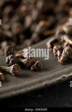Cumulo di materie, essiccato cannella dei boccioli spice sulla piastra metallica sul rustico tavolo nero lo sfondo con il fuoco selettivo Foto Stock