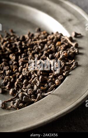 Cumulo di materie, essiccato cannella dei boccioli spice sulla piastra metallica sul rustico tavolo nero lo sfondo con il fuoco selettivo Foto Stock